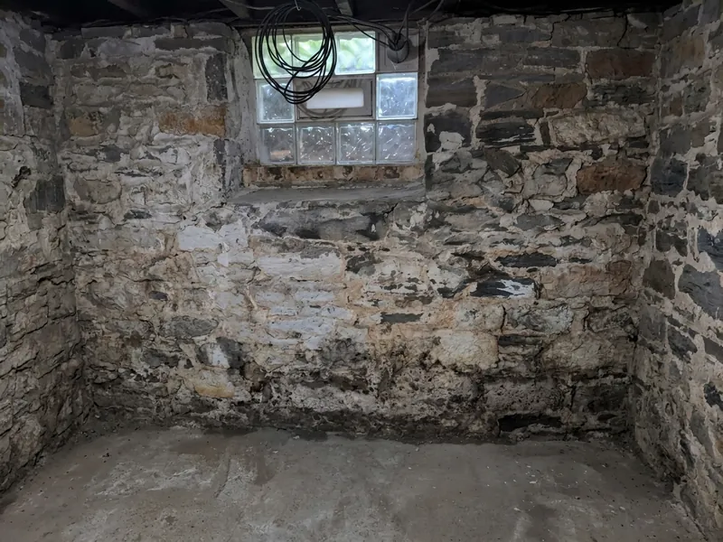 Damp band along the bottom of an old stone cellar wall